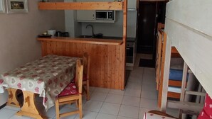 A compact kitchen with a wooden counter and a dining area with a table and chairs. - Studio 4 Pers, Near Chairlift, South Balcony (Châtel)