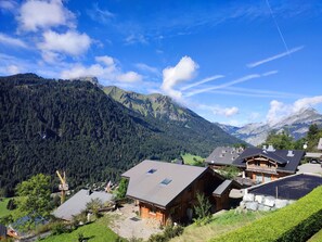 Un village de montagne aux maisons en bois, doté d’un télésiège et surplombé d’un ciel bleu azur.