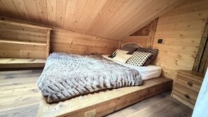 Un dormitorio de cabaña de madera con una cama individual, una mesita de noche y un banco empotrado.