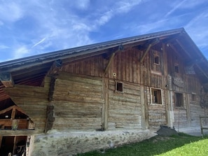 A rustic wooden building with a sloped roof, a visible entrance, and a small porch area.