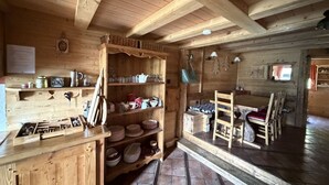 A wooden interior with a kitchen area, shelves with dishes, and a dining table. - 4-Room Chalet, 8 People, Wifi, Parking, Châtel (Châtel)