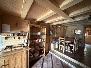 A wooden interior with a kitchen area, shelves with dishes, and a dining table. - 4-Room Chalet, 8 People, Wifi, Parking, Châtel (Châtel)