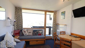 A cozy room with a sofa, a small table, and a window with curtains.
