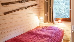 A wooden cabin room with a bed, wooden walls, a window with curtains, and a lamp. - 3-room apartment for 6 people with balcony in Châtel (Châtel)