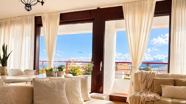A spacious living area with a sofa, a coffee table, and a view of the cityscape through large windows. - Luxury view apartment 10min from Athens airport (Koropi)