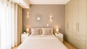 A bedroom with a bed, nightstands, a wall-mounted light fixture, and a wardrobe. - Luxury view apartment 10min from Athens airport (Koropi)