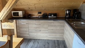 Kompakti keittiö, jossa on puukuvioiset kaapit, mikroaaltouuni, leivänpaahdin, kahvinkeitin ja astianpesukone.
