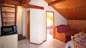 A compact room with a kitchenette, a bed with a red and white patterned bedspread, and a wooden ceiling. - 3-room apartment for 7 in Châtel, near center and lifts, with balcony and parking (Châtel)
