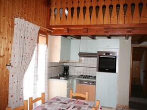 A compact kitchen with a Bosch oven, a gas stove, and a sink. There is a dining table with a checkered tablecloth.