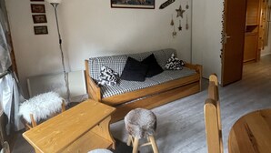 A cozy living room with a checkered sofa, a wooden table, and a small stool. There is a picture on the wall and a lamp to the left. - Chalet in Châtel, Near Slopes, 5 Pers, Parking Included (Châtel)