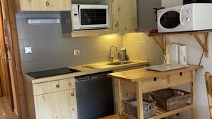 A compact kitchen with a built-in microwave, a sink, and a small wooden table with baskets. - Chalet in Châtel, Near Slopes, 5 Pers, Parking Included (Châtel)