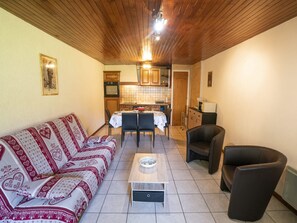 A cozy living room with a sofa, a coffee table, and a dining area with chairs and a table.