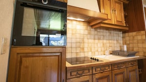 A kitchen with wooden cabinets, a stainless steel oven, a tiled backsplash, and a countertop with a sink and a dish rack. - Apartment for 5 near cable car, pets allowed (Châtel)