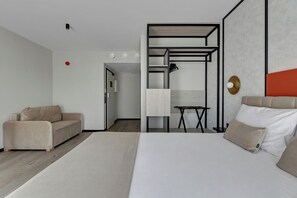 Een moderne hotelkamer met een bed, een bank, een bureau en een kledingkast.