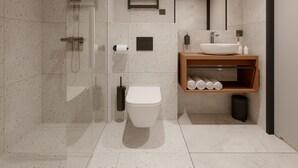 A modern bathroom with a glass shower enclosure, a white toilet, a wooden vanity with a sink, and a towel rack.
