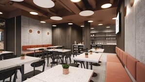 A modern restaurant interior with round tables, cushioned booths, and a bar area.