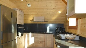 A modern kitchen with wooden cabinetry, stainless steel appliances, and a black countertop.