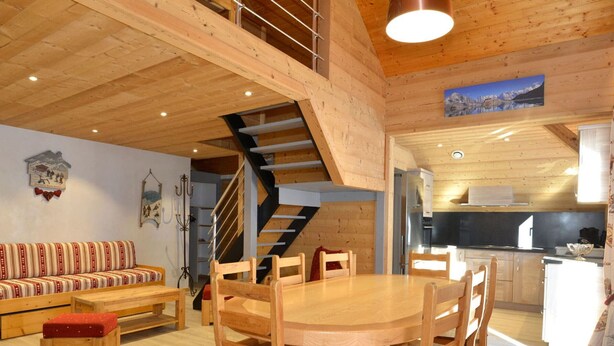 A wooden interior with a dining area, staircase, and kitchen.