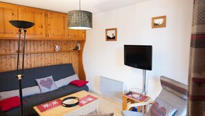 Een gezellige woonkamer met een bank, een salontafel, een televisie en een lamp.