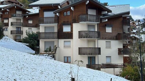 A multi-story building with wooden balconies and a ski slope in the foreground. - Charming 2-Room Apartment, Sleeps 5, Terrace, Parking, Pet-Friendly (Châtel)