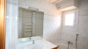 Ein Badezimmer mit Waschbecken, Spiegel und Badewanne.