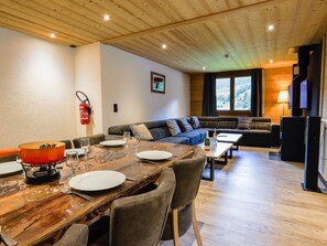 A cozy living area with a wooden dining table set for four, a sofa, and a television.