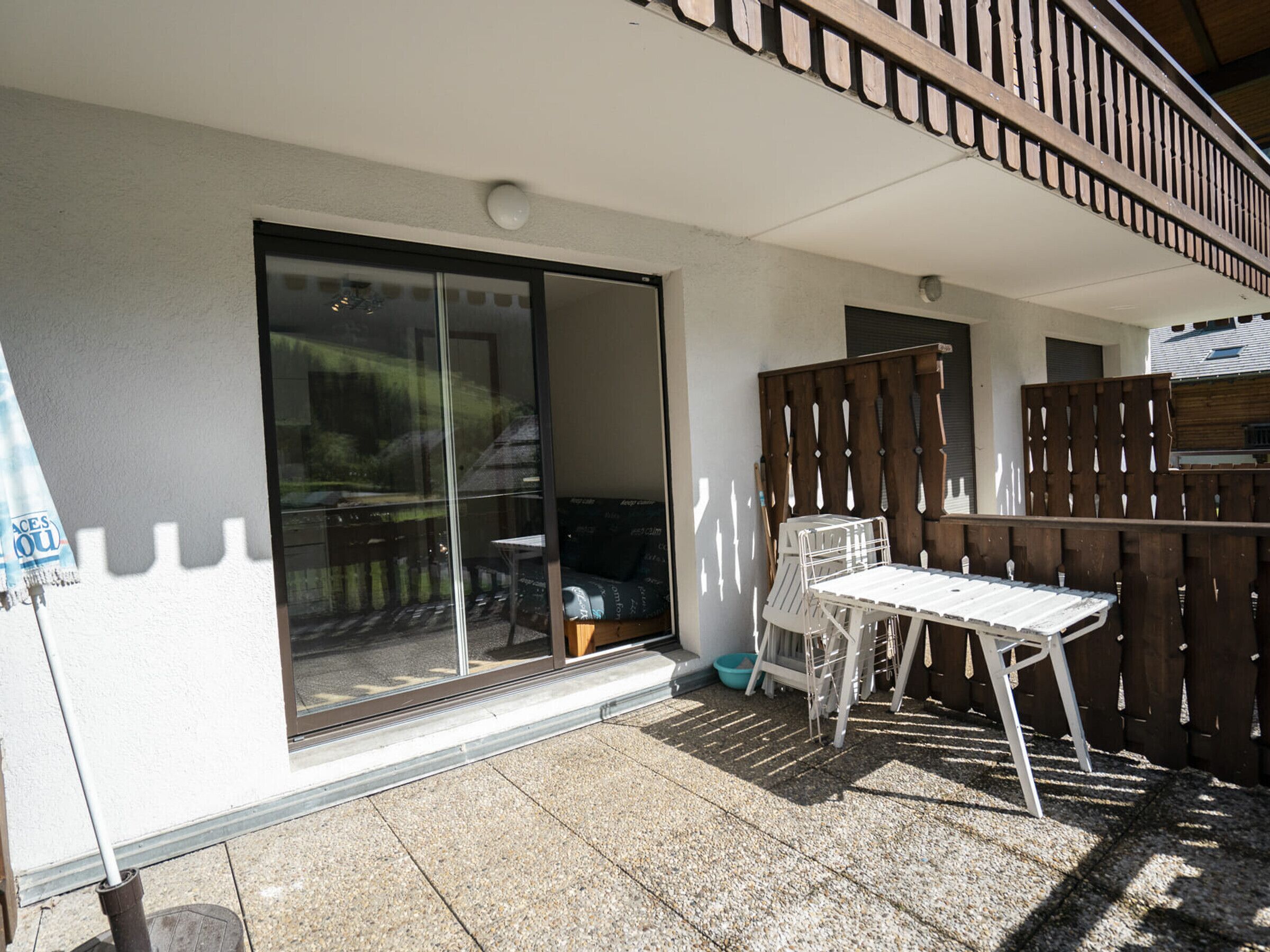 A patio area with a sliding glass door, a small table, and a wooden fence.
