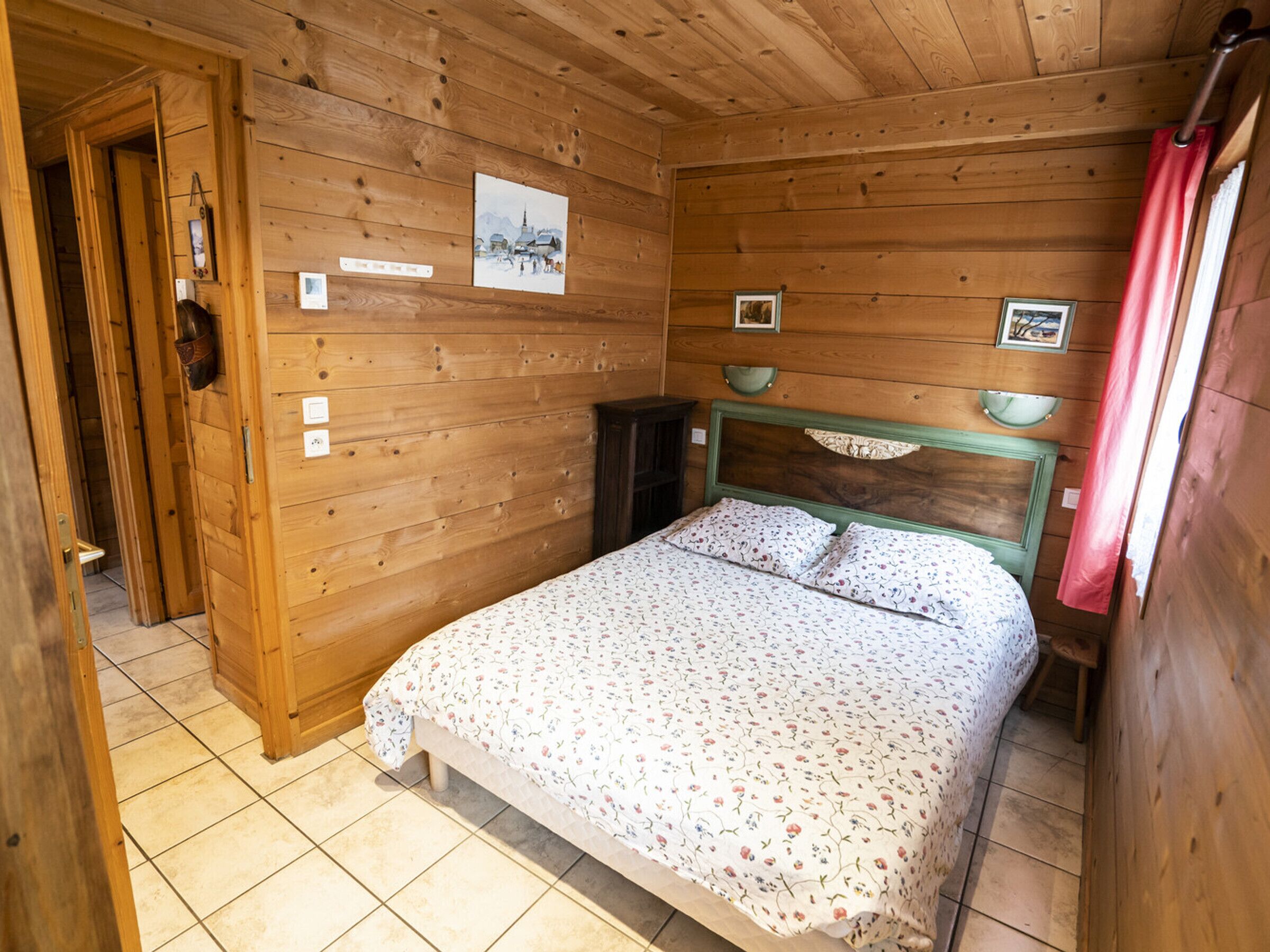 Une pièce en bois avec un lit, une porte et un mur orné de tableaux.
