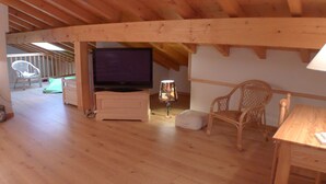 An attic room with a wooden ceiling, a television, a lamp, a chair, and a table. - Calm Duplex T4 with parking, pets allowed in Samoëns (Samoëns)