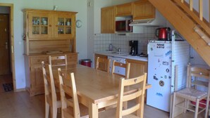 A kitchen with wooden cabinets, a dining table, chairs, a microwave, a coffee maker, and a refrigerator. - Calm Duplex T4 with parking, pets allowed in Samoëns (Samoëns)