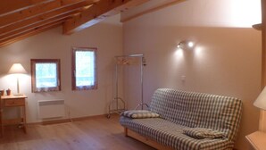A cozy room with a wooden ceiling, a checkered sofa, a small table with a lamp, and a radiator. - Calm Duplex T4 with parking, pets allowed in Samoëns (Samoëns)