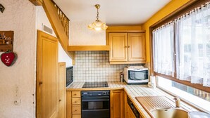 Una cocina compacta con armarios de madera, un microondas, un horno y un lavabo.