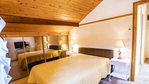 Un dormitorio acogedor con una cama grande, mesitas de noche con lámparas, un televisor y un espejo.