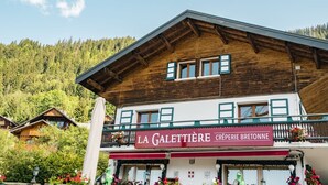 Un edificio de estilo chalete tradicional con fachada de madera y un balcón lleno de flores.