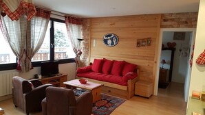 A cozy living room with a red sofa, brown armchairs, a wooden coffee table, and a television. - Châtel Apartment 2 rooms, 5 ppl, South Balcony, Parking (Châtel)