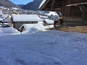A snowy village with wooden buildings and a wooden structure in the foreground.