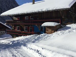 A wooden chalet with a balcony, surrounded by snow-covered mountains. - Cozy 2-BR Apartment Sleeps 6 – Near Village & Lifts, Pets Welcome, Balcony, Parking! (Châtel)