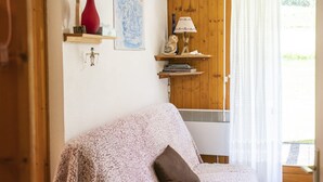 Un salon chaleureux avec une porte en bois, un vase rouge, une carte et une lampe posée sur une étagère.