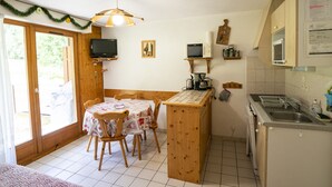 Une cuisine compacte avec un coin repas, des meubles en bois, une télévision et un four à micro-ondes.