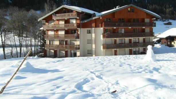 Un hôtel à plusieurs étages, doté de balcons, situé dans une région montagneuse enneigée.