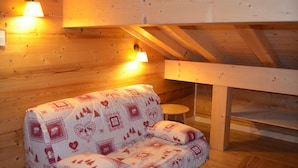 Een gezellige kamer met houten wanden, een bank en twee wandlampen.
