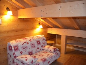 Ein gemütliches Zimmer mit Holzwänden, einer Couch und zwei Wandleuchten.