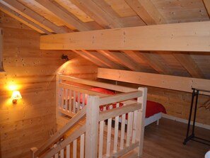 Ein Zimmer mit Holzboden, einem Etagenbett, einem kleinen Tisch und einer Wandlampe.