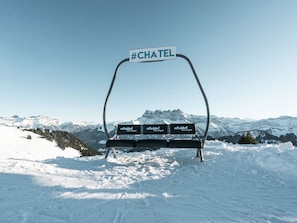 A ski lift chair with a sign reading "#CHATEL" and three identical signs below it.