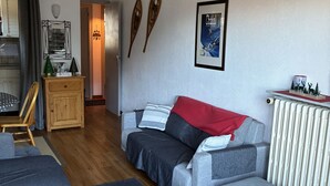 Een moderne woonkamer met een grijze bank, een houten kast en een lijst met een afbeelding aan de muur.