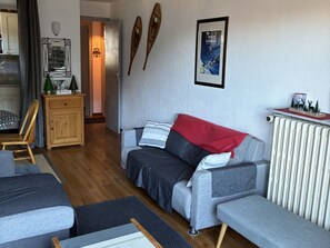 A modern living room with a grey sofa, wooden cabinet, and a framed picture on the wall.