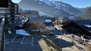 Een bergstad met gebouwen, een parkeerplaats en besneeuwde bergen op de achtergrond.