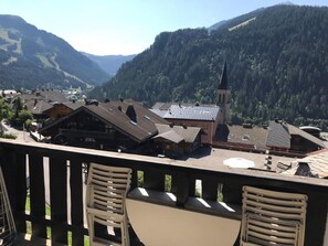 A mountain village with traditional wooden buildings, a church, and a view of the surrounding hills. - Cozy apartment 5 people, near cable car, west balcony (Châtel)