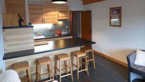 A modern kitchen with wooden cabinets, a black countertop, and wooden stools.