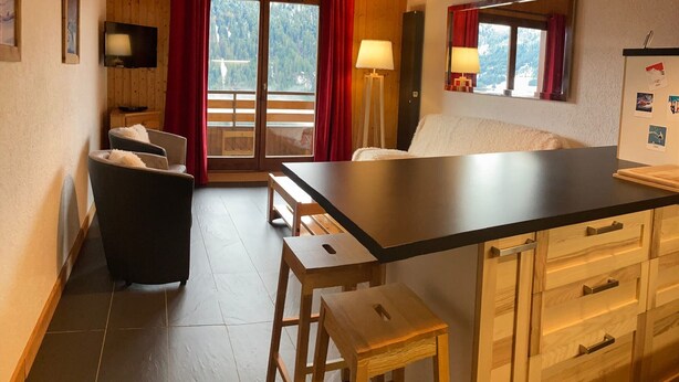 A cozy kitchen with wooden cabinets, a central island, and a dining area with chairs.